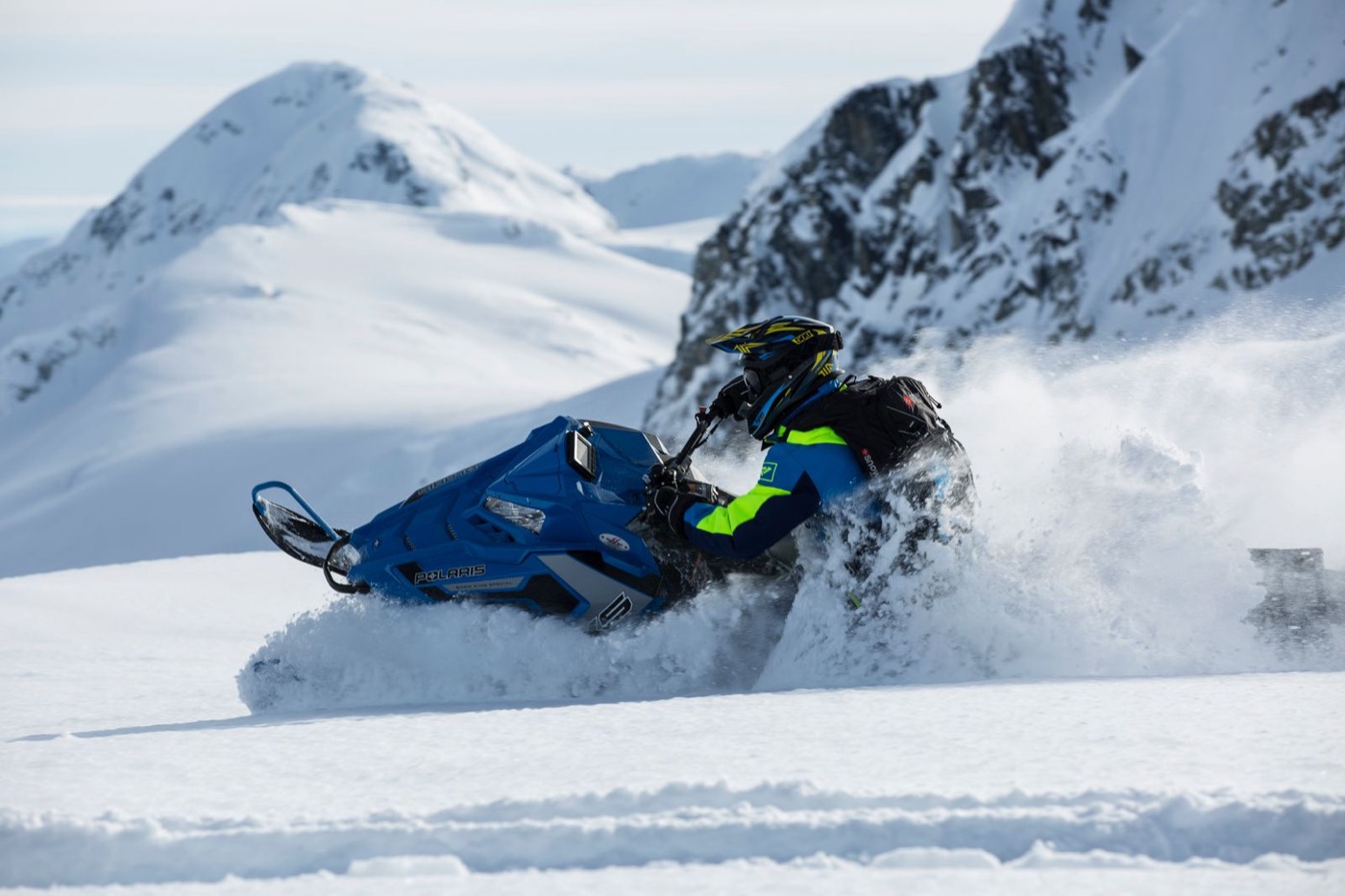 Rider carving deep powder on a mountain sled