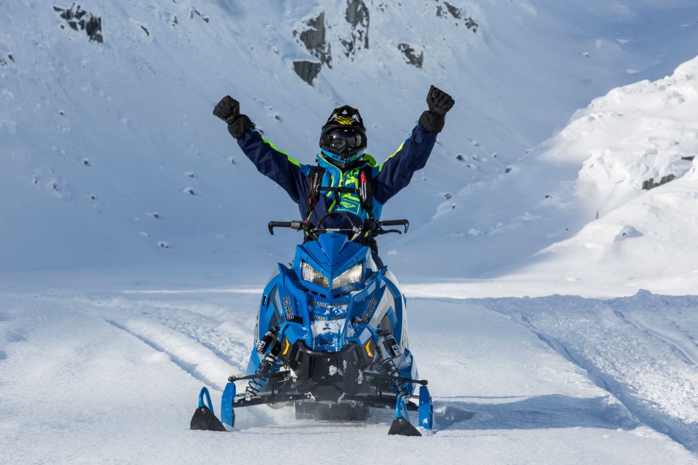 Rider celebrating on a mountain snowmobile